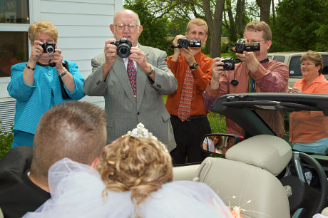 Retired wedding photographer joins in with the rest of the family as Kristen and Joel Buchanan pose in their get-away car.