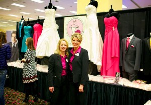 Girls in White Satin in front of their bride dress booth at wedding show