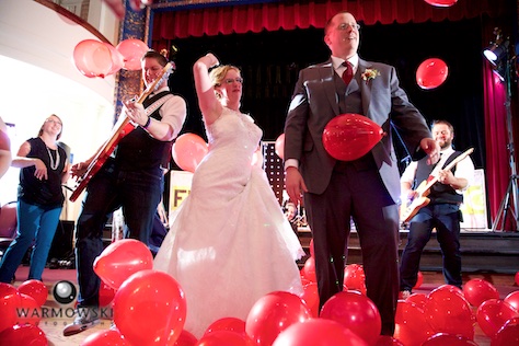 Amy & Ryan dance with a member of Fun DMC during their wedding reception at the Hoogland Center for the Arts in Springfield. With playful mashups and an endless supply of energy, the bride and groom said the live wedding band helped to make the night into a real party. Wedding photography by Tiffany & Steve of Warmowski Photography.