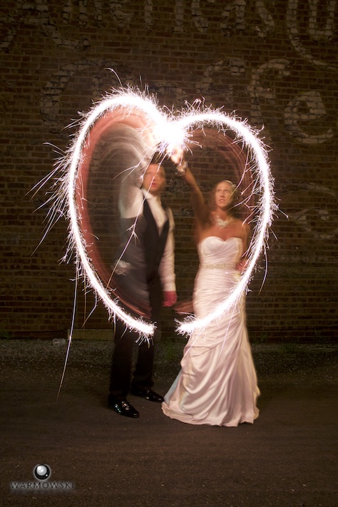 Amber & Ryan end the 4th of July night with sparklers, outside of reception hall Hamilton's 110 North East. Wedding photography by Steve & Tiffany Warmowski